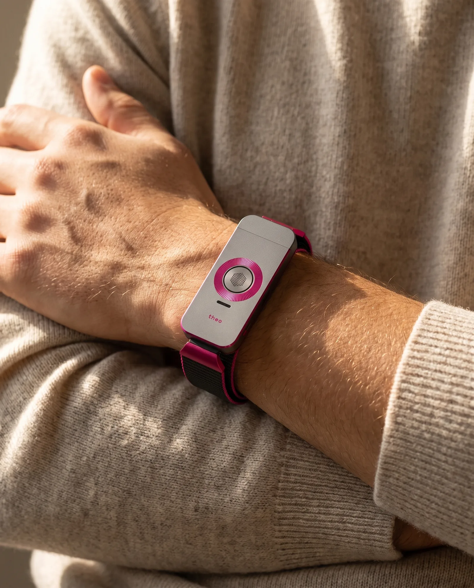 Arms crossed in a cream knit sleeve, the Iron / Fuchsia band worn without notice.