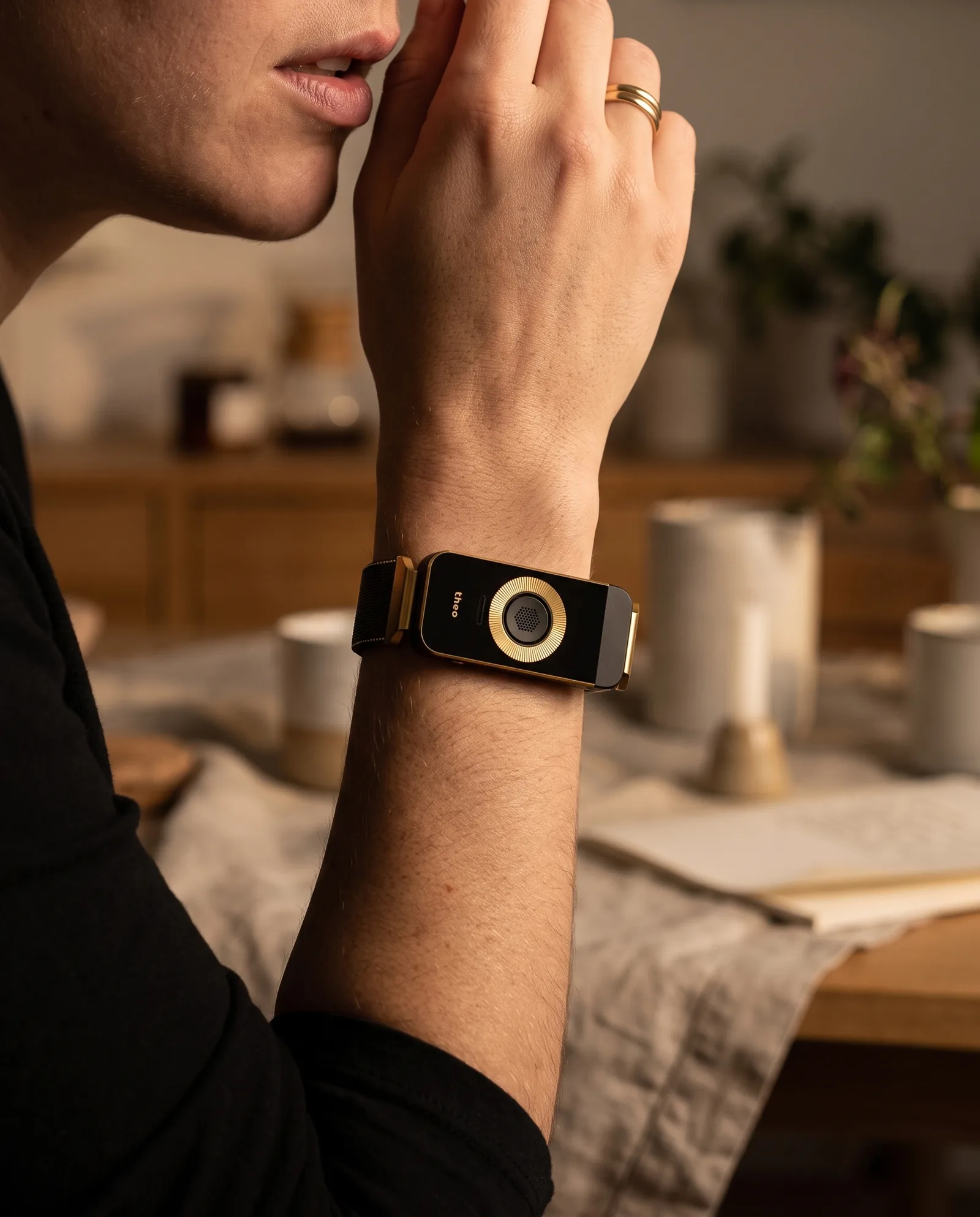 A woman raises her wrist to speak, the Black / Gold band close to her mouth.